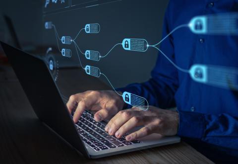 Person on laptop with encryption symbols around them to represent blockchain